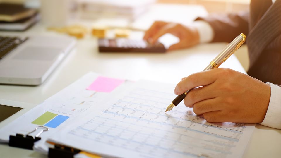 An accountant reviewing a spreadsheet with a pen and calculator