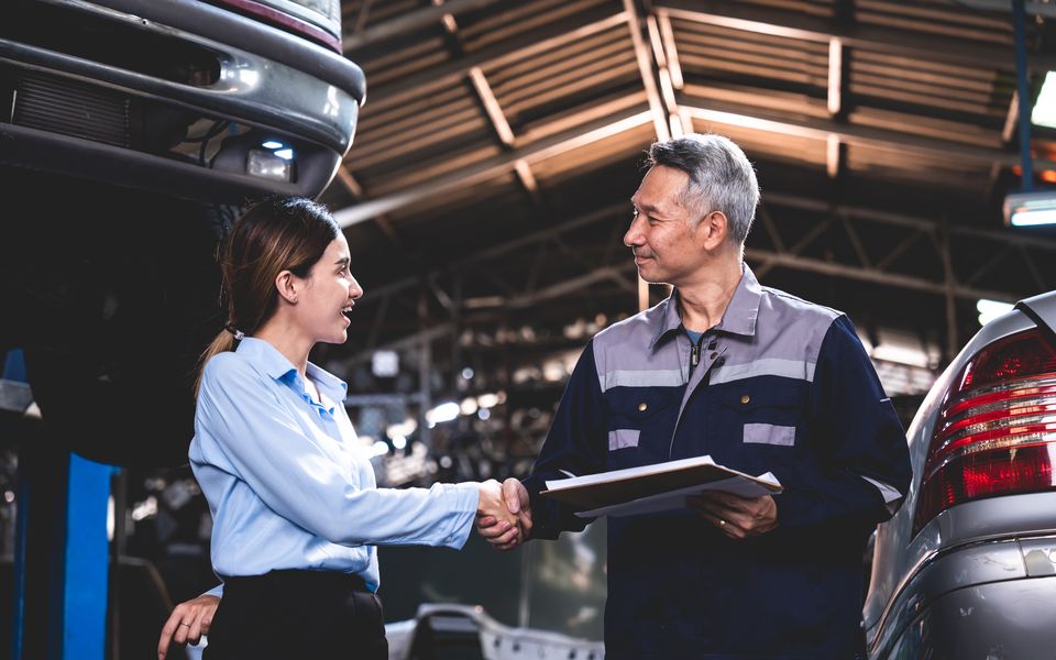 A service advisor shaking hands with a technician over a repair order