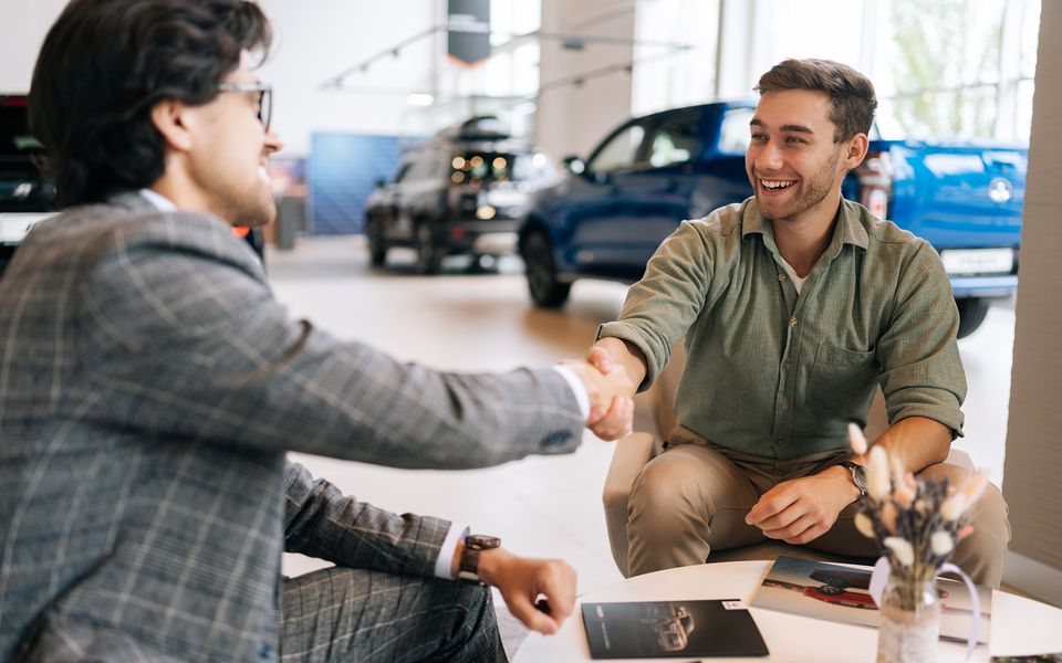 A handshake on a dealership showroom floor