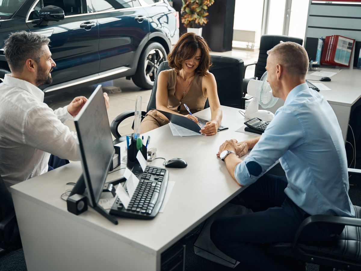 Customers signing paperwork at a dealership desk